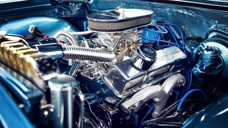 Motorraum eines blauen Oldtimers mit verchromtem Ventildeckel "Impala", Holley-Vergaser und blauen Zündkabeln